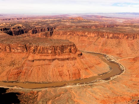 Aerial view of an arid, craggy landscape with a river running through it. Horizontal shot.