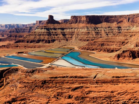 Aerial view of an arid, craggy landscape surrounding tailing ponds. Horizontal shot.