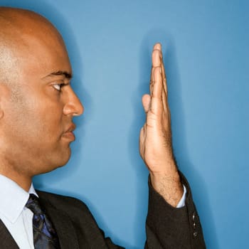African American businessman holding hand in front of face.