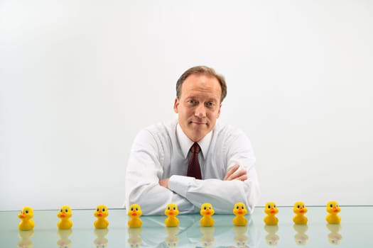 Portrait of middle aged  Caucasian businessman sitting at desk with ducks in a row.