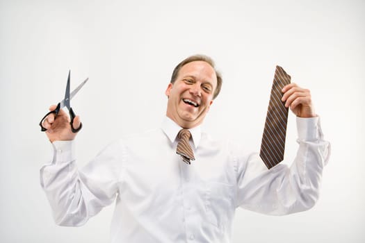 Caucasian middle aged businessman holding cut off necktie and scissors smiling.