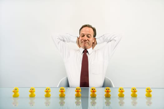Portrait of middle aged  Caucasian businessman sitting at desk with ducks in a row.