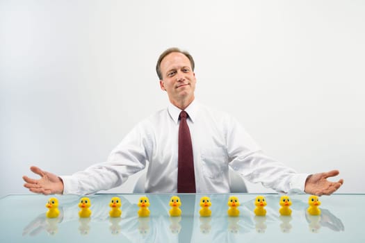 Portrait of middle aged  Caucasian businessman sitting at desk with ducks in a row.
