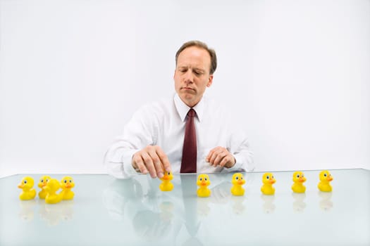 Portrait of middle aged  Caucasian businessman sitting at desk putting ducks in a row.