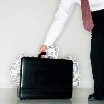 Caucasian middle aged businessman carrying briefcase overflowing with money.