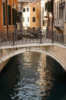 Canal and walking bridge surrounded by Old World buildings in Venice, Italy. Vertical shot.