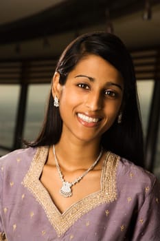 Portrait of an attractive young Indian woman wearing traditional clothing and smiling at the camera. Vertical shot.