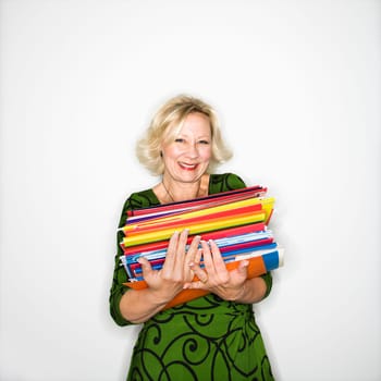 Caucasian middle aged businesswoman carrying stack of folders smiling.