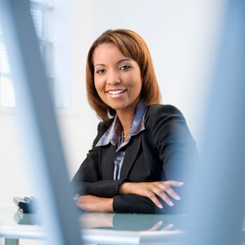 Portrait of African American businesswoman sitting at office desk smiling.