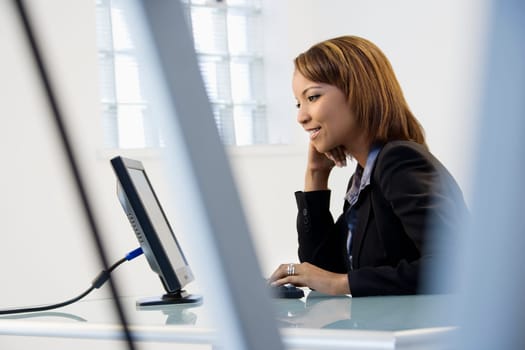 Portrait of African American businesswoman sitting at office desk working on computer.