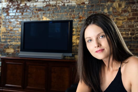Portrait of pretty young Caucasian woman with television in background.
