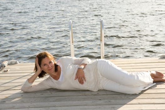 Woman relaxing on dock, Lake of the Woods, Ontario, Canada