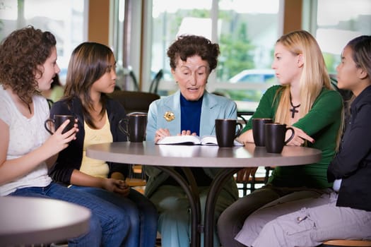 Group of girls listening to senior woman in restaurant