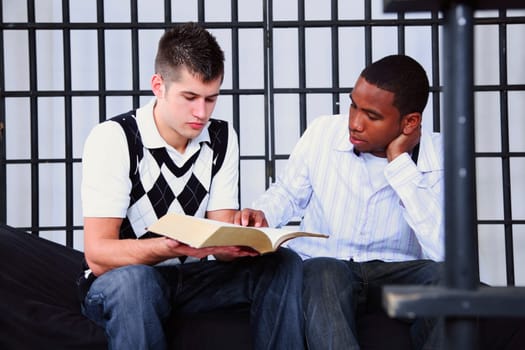 a young man reading the bible to another young man in jail