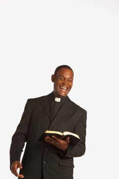 a man wearing a clerical collar and laughing while holding an open bible