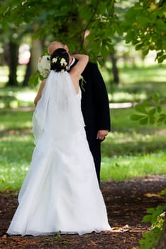 Bride and groom kissing in park