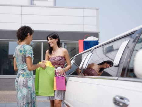 friends with shopping bags and limousine