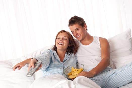 Couple lying in bed watching television
