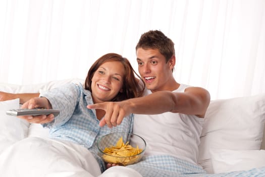 Couple lying in bed watching television