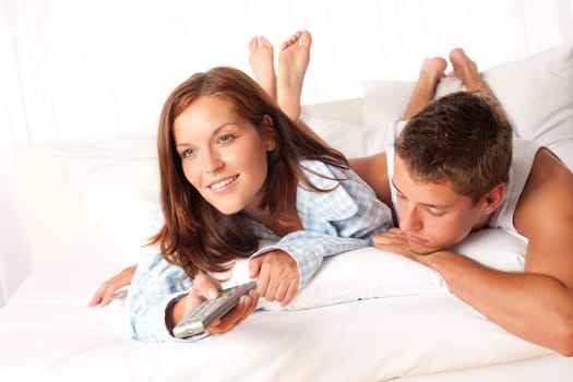 Young couple enjoy watching TV in bed