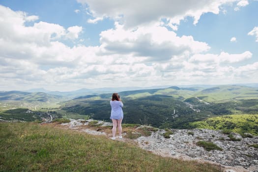 woman from above on the mountain looks into the distance admiring nature journey hiking