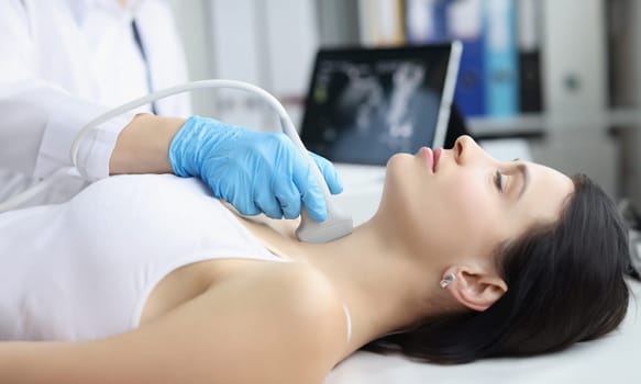 Portrait of ultrasound scanning diagnostic of woman thyroid gland in clinic, doctor runs ultrasound sensor over patients neck with gel. Diagnostics concept