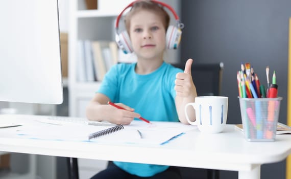 Portrait of schoolgirl studying online at home, wear headset, show thumbs up, drawing. Childhood, development, preschool class, remote education concept