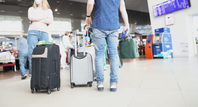 Close-up of man going on trip, flight delay, stand in line to checkin in airport terminal. Ready for vacation, packed suitcase, holiday, tourism concept