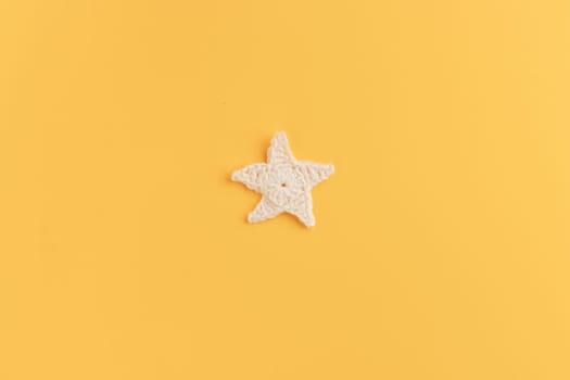 The white and yellow  crocheted star on a bright background with copy space / pattern