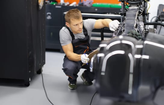 Portrait of serious handyman work with tool, fix damaged motorbike in workshop. Mechanic repair old detail. Pit stop, service help, maintenance concept