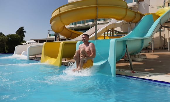 Portrait of middle aged man having fun, sliding at water park, summer vacation. Person laugh, enjoy holiday. Leisure, summertime, water fun, trip concept