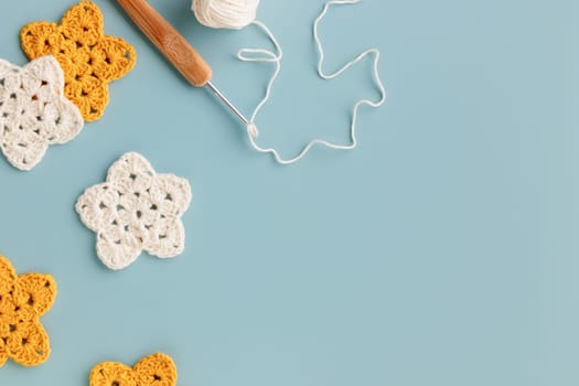 The white and yellow crocheted stars with a hook on a blue background with copy space