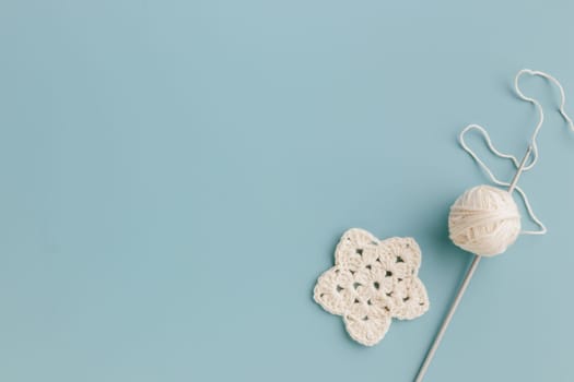 The white crocheted star with a hook on a blue background with copy space