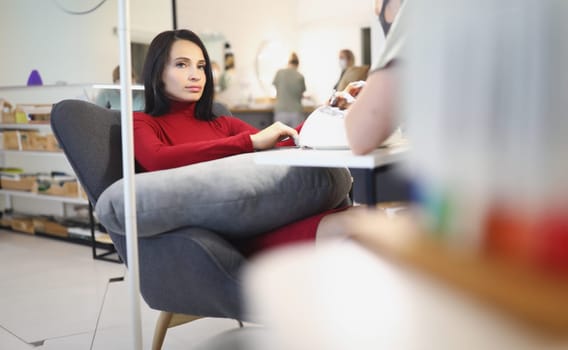 Portrait of bored lady client on manicure and pedicure appointment in beauty salon. Wellness procedure in luxury salon. Beautician, self love, care concept