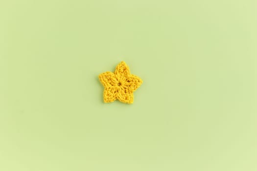 Yellow crocheted flower on a green background