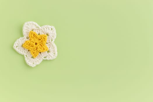 Yellow crocheted flower on a green background