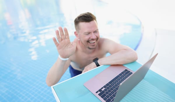Portrait of middle aged male talk to friend online via video call, guy wave hello and smile. Chilling on vacation, get rest, holiday fun, resort concept