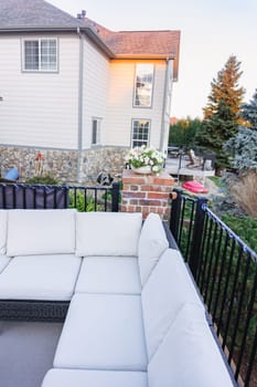 Morning on a summer day. Fully furnished backyard patio with a grill, sitting area, and umbrella.