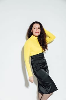 brunette woman posing against a white wall in a room