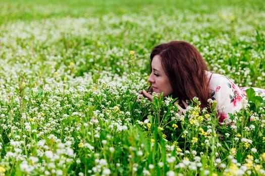 woman smells flowers in a green clearing