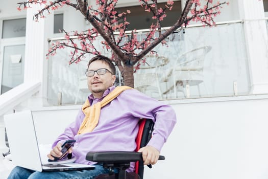 portrait of a special person with disabilities in a tree with a laptop and a phone