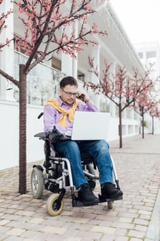 a special person with disabilities with a laptop talking on the phone in the park