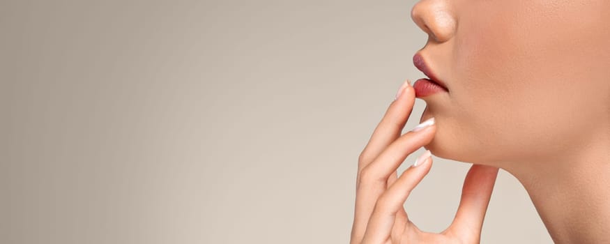 Calm european young woman with perfect skin touching hands to red lips, isolated on gray studio background, cropped, close up. Beauty care, nude makeup, moisturizing, panorama