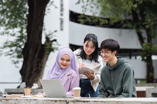 A group of happy multiracial students at the college with Muslim and Asian students grouped together sat on benches in the campus break area. Read books or study for exams together..