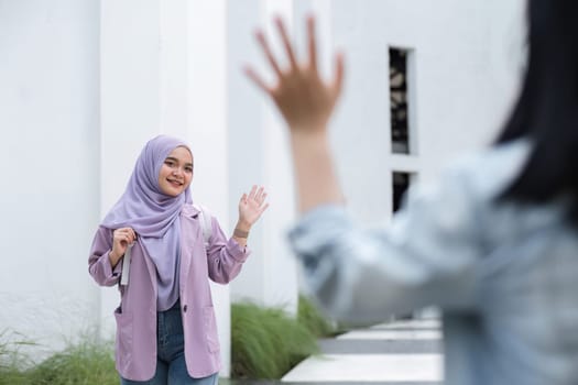Young Muslim student greets fellow college students as they meet during free time.