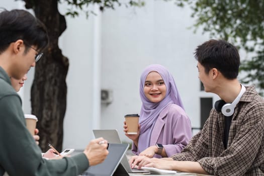 A multiracial group of students at the college, including Muslim and Asian students, sat on benches in a campus break area. Read books or study for exams together..