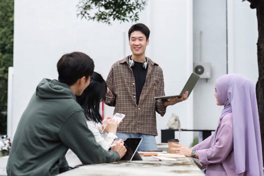 A multiracial group of students at the college, including Muslim and Asian students, sat on benches in a campus break area. Read books or study for exams together..