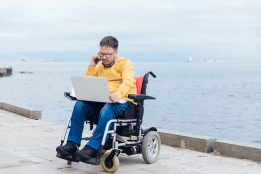 a special person with disabilities by the sea on a walk at work with a laptop