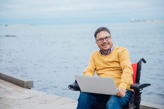 a special person with disabilities by the sea on a walk at work with a laptop