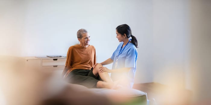 Physical therapist caregiver Asian and Caucasian senior women trust moving hand in rehabilitation. Physiotherapy healthcare, Medical caregiver consulting disabled elderly patient at home.